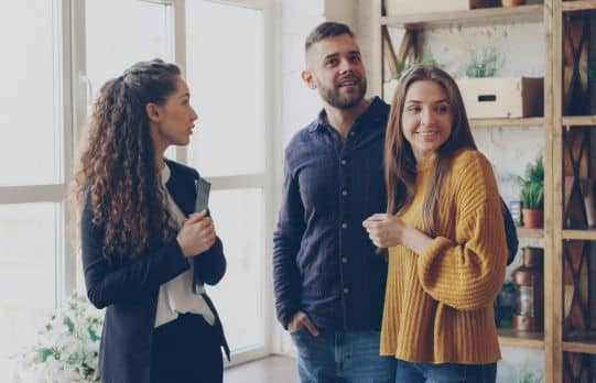Real estate agent showing a young couple around a bright home during a property tour in Bluffton or Hilton Head Island.