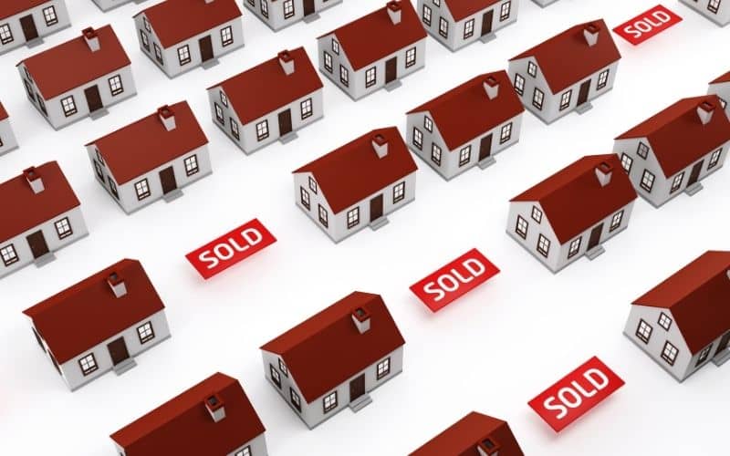rows of illustrated white houses with red roofs with three red sold banners